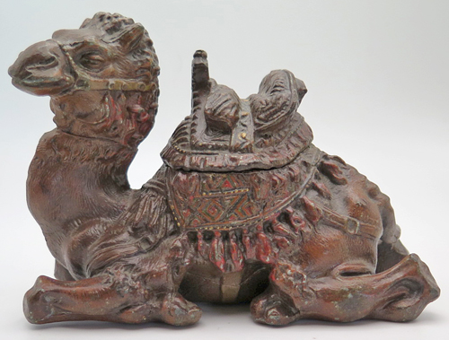 ITEM #6656: METAL CAMEL INKEWLL WITH GLASS INCERT. HILIGHTS HAND PAINTED IN RED. ORNATE DETAIL. 4" tall x 5" length x 2.5 width. 
