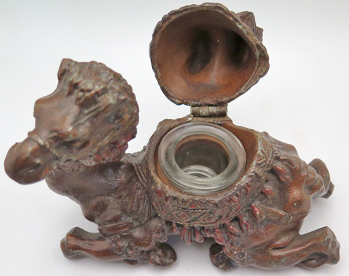 ITEM #6656: METAL CAMEL INKEWLL WITH GLASS INCERT. HILIGHTS HAND PAINTED IN RED. ORNATE DETAIL. 4" tall x 5" length x 2.5 width. 