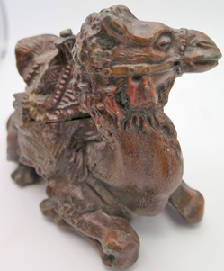 ITEM #6656: METAL CAMEL INKEWLL WITH GLASS INCERT. HILIGHTS HAND PAINTED IN RED. ORNATE DETAIL. 4" tall x 5" length x 2.5 width. 