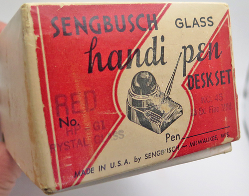 ITEM #6665: SENGBUSCH CLEAR GLASS HANDIPEN DESK SET. FOUNTAIN PEN HAS EXTRA FIN NIB. NEW OLD STOCK IN ORIGINAL RED PACKAGING. CONTAINS DIRECTIONS. CIRCA 1920.