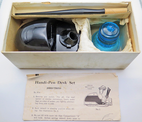ITEM #6666: SENGBUSCH HANDIPEN PLASTIC BLACK INKWELL + PEN STAND WITH UNIQUE BLUE GLASS BELL. BELL PHONE SYSTEMS EMPLOYEE OFFICE ISSUED. PEN STAND STATES "PROPERTY OF BELL SYSTEMS". NEW OLD STOCK IN ORIGINAL GREEN PACKAGING WITH INSTRUCTIONS. BLUE GLASS BELL SAYS "SAVE TIME SAVE STEPS". PEN IS EXTRA FINE.