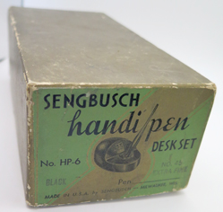 ITEM #6666: SENGBUSCH HANDIPEN PLASTIC BLACK INKWELL + PEN STAND WITH UNIQUE BLUE GLASS BELL. BELL PHONE SYSTEMS EMPLOYEE OFFICE ISSUED. PEN STAND STATES "PROPERTY OF BELL SYSTEMS". NEW OLD STOCK IN ORIGINAL GREEN PACKAGING WITH INSTRUCTIONS. BLUE GLASS BELL SAYS "SAVE TIME SAVE STEPS". PEN IS EXTRA FINE.