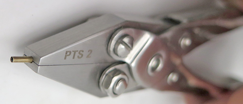 ITEM #PTS2: SIMPLE SNOKEL PLIERS. PARALLEL JAW SET OF PLIERS WITH A 1/16" GROVE. THE SLOT/GROVE RUNS FROM THE FRONT OF THE JAWS THROUGH THE BACK OF THE PLIERS. USED TO INSERT AND REMOVE SNORKEL TUBES WITHOUT DAMAGING THEM. 